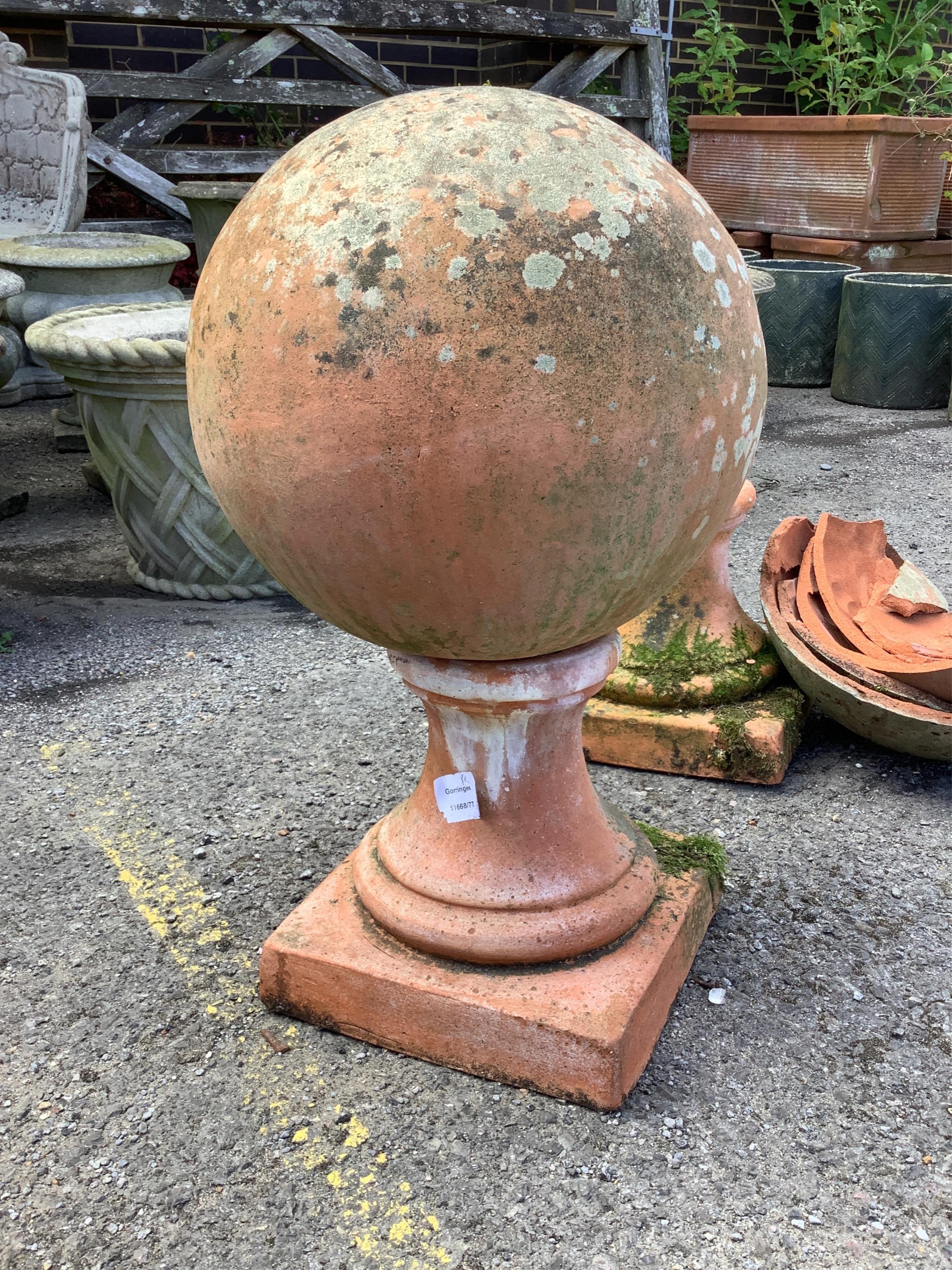 A large pair of weathered terracotta sphere garden ornaments, one in need of restoration, height 58cm. Condition - one good, one poor